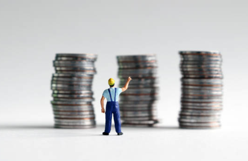 Worker in buke dungarees standing in front of stacks of coins